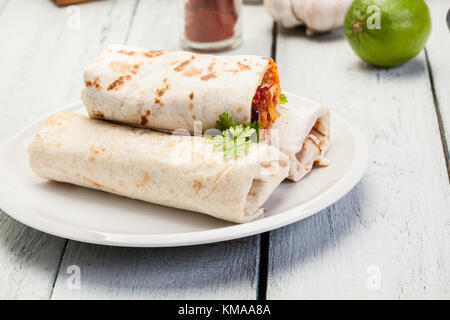 Burrito messicano si avvolge con carni macinate, fagioli e verdure su una piastra Foto Stock