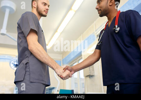 Due giovani medici stringe la mano ad ogni altro. multirazziale team di giovani medici. Foto Stock