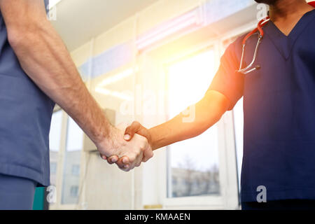 Due giovani medici stringe la mano ad ogni altro. multirazziale team di giovani medici. Foto Stock