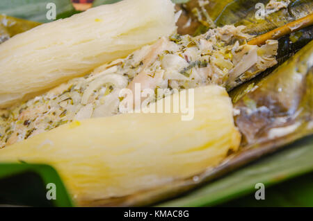 Close up di deliziosi piatti tipici alimenti amazonia, pesce cucinato in una foglia con yucca e piantaggine, servita in un piatto di legno su una tavola di legno Foto Stock