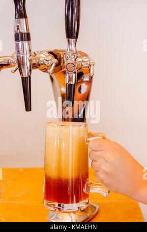 Barman mano alla birra tocca una colata di progetto birra chiara con sede di servizio in un ristorante o pub in uno sfondo sfocato Foto Stock