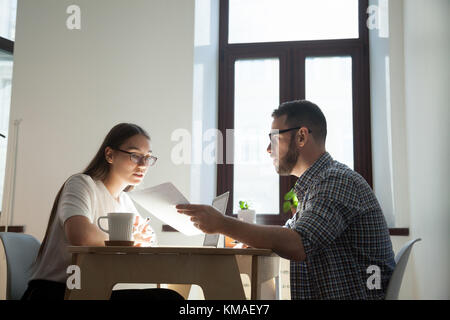 Imprenditore e imprenditrice a discutere i problemi del lavoro. gruppo di dipendenti millenario seduto in ufficio e risoluzione di domanda di lavoro Foto Stock
