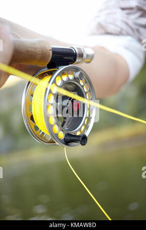 Vista ravvicinata del lato asta e mulinello con nylon giallo linea di un pescatore a mosca la pesca all'aperto Foto Stock