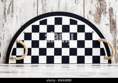 Vassoio con in bianco e nero la dama pattern e maniglie sul bianco sullo sfondo di legno Foto Stock