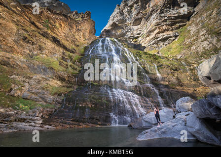 Hikker womann guardando equiseto cascata in Ordesa national park, Pirenei, Spagna. Foto Stock