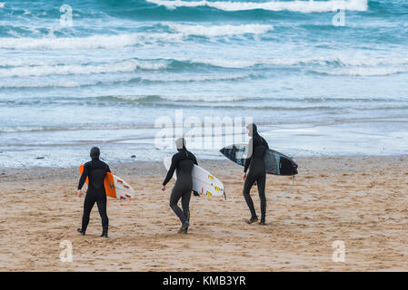 Navigare in Cornovaglia - tre surfers camminando sul Fistral Beach Newquay Cornwall Regno Unito. Foto Stock