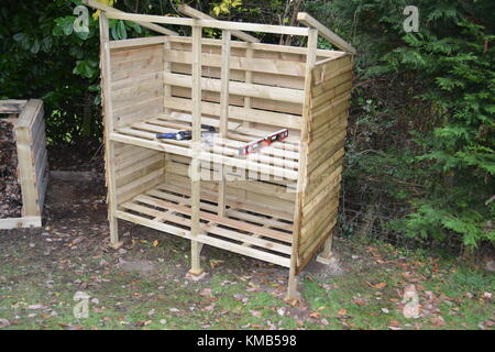 Legname store log in costruzione in giardino con composto ammucchi fatta di ri-uso dei pallet pieni di foglie e di erba tagliata che mostra anche a sinistra Foto Stock