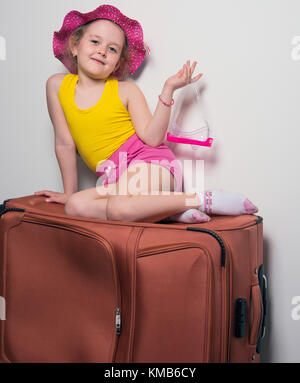 Bambina in un cappello seduti sulle loro valigie, in attesa del viaggio Foto Stock