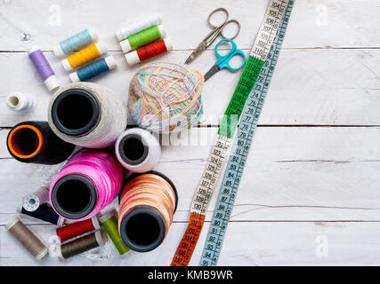 Colorata per cucire gli steli di linea, grandi e piccole, forbici e nastro di misurazione sulla parte superiore di un bianco sullo sfondo di legno piano portapaziente, concetto e idea Foto Stock