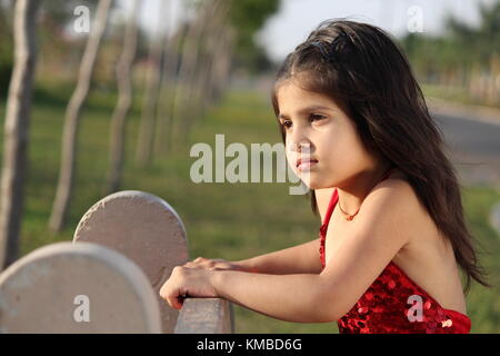 Carino ragazza seduta in abito rosso bellissimo capretto in estate Foto Stock