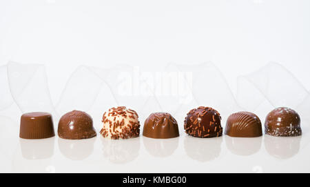 Praline di cioccolato in una fila con trasparente nastro bianco, spazio di testo Foto Stock