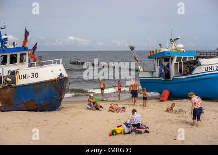 I vacanzieri si divertono tra le barche da pesca sulla spiaggia del resort Mielno. Foto Stock