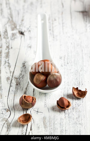 Intero e nocciole tritate su bianco tavolo in legno Foto Stock