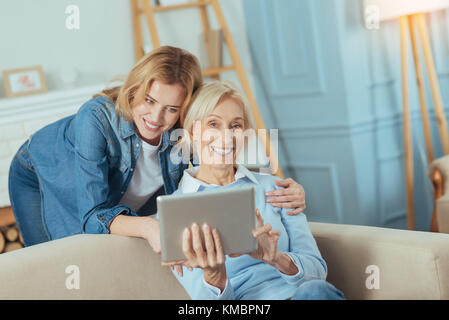 Titolare di pensione o di rendita positiva di ridere mentre suo nipote in piedi dal suo lato Foto Stock