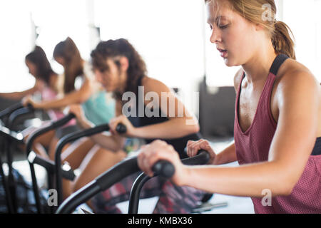 Giovane donna che usa la bicicletta ellittica in classe di esercizio Foto Stock