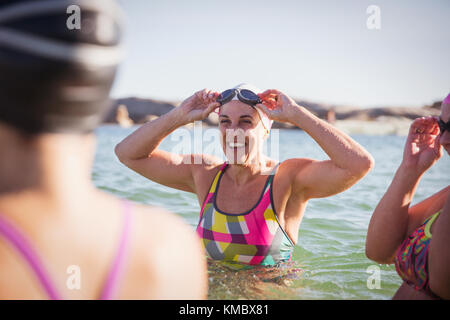 Donna sorridente open water nuotatori guadare in sunny ocean Foto Stock