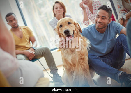 Uomo che accarezzano il cane nella sessione di terapia di gruppo Foto Stock