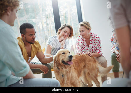 Persone che accarezzano il cane nella sessione di terapia di gruppo Foto Stock