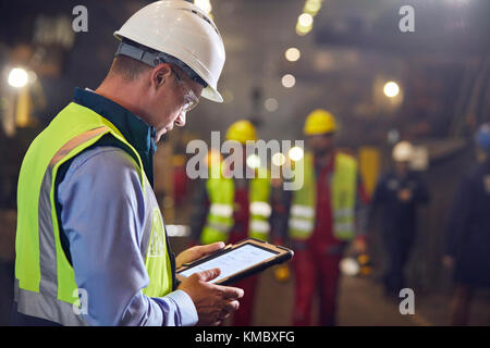 Steelworker che utilizza un tablet digitale nella acciaieria Foto Stock