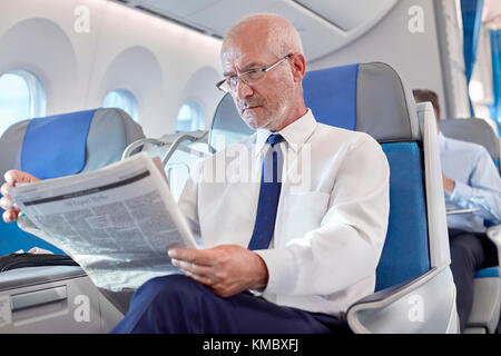 Giornale di lettura dell'uomo d'affari anziano sull'aeroplano Foto Stock