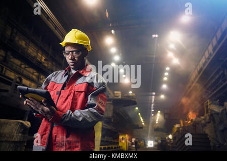 Steelworker che utilizza un tablet digitale nella acciaieria Foto Stock