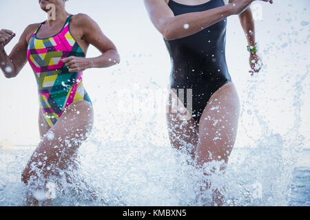 Femmina acqua aperta nuotatori in esecuzione e spruzzi in ocean surf Foto Stock