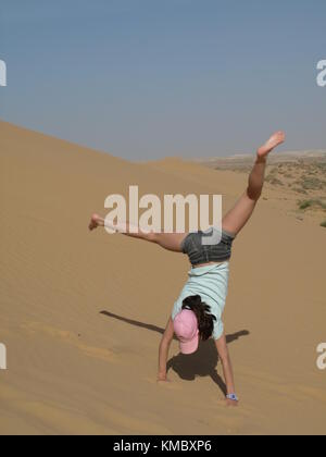 Ragazza in piedi sulla sua mano su di una duna di sabbia Foto Stock