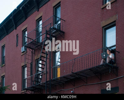 Uomo seduto sulla via di fuga in caso di incendi con computer portatile Brooklyn NYC Foto Stock