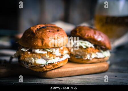 Rustico hamburger di pesce con coleslaw e birra Foto Stock