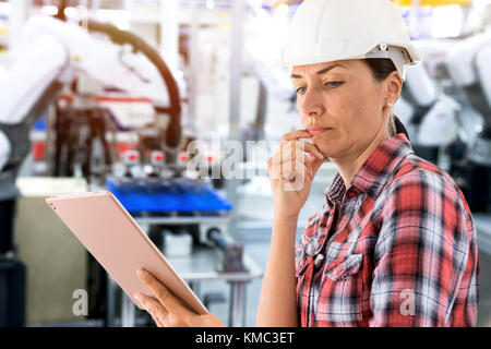 Ingegnere femmina utilizzando tablet con macchina di monitoraggio in tempo reale del software di sistema. Automazione di sfocatura braccio di robot macchina in smart factory industria iot 4a,di Foto Stock