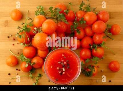 Tamoto succo con pepe e pomodori ciliegia sulla tavola in legno isolato Foto Stock