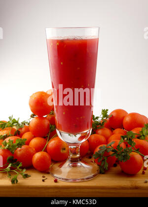 Tamoto succo con pepe e pomodori ciliegia sulla tavola in legno isolato Foto Stock