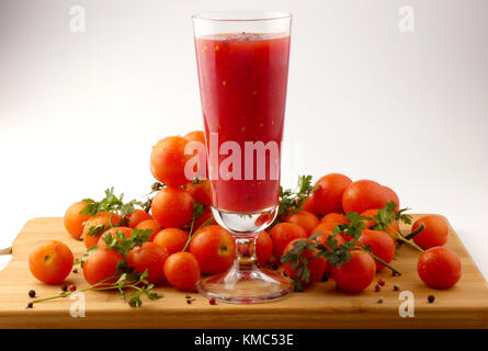 Tamoto succo con pepe e pomodori ciliegia sulla tavola in legno isolato Foto Stock