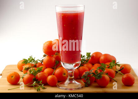 Tamoto succo con pepe e pomodori ciliegia sulla tavola in legno isolato Foto Stock