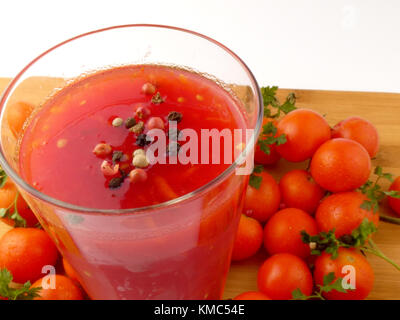 Tamoto succo con pepe e pomodori ciliegia sulla tavola in legno isolato Foto Stock