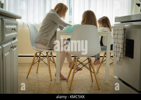 Madre aiutando i suoi figli in studi Foto Stock