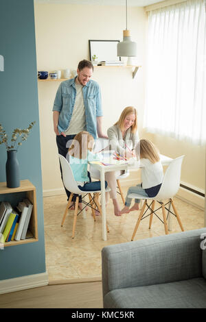 Madre e padre che aiutano i loro figli negli studi Foto Stock