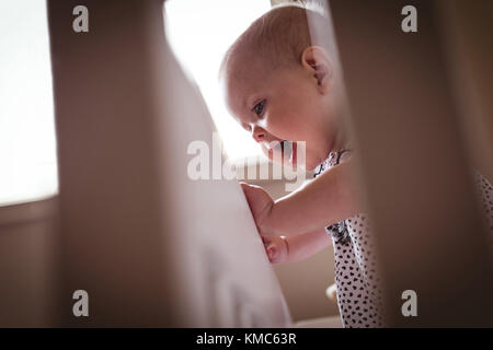 Ragazza carina in piedi in culla Foto Stock