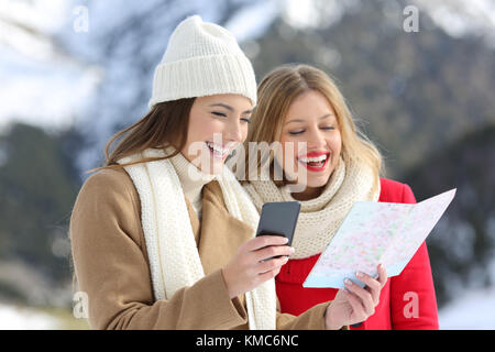 Due turisti felici la lettura di una mappa su carta in vacanze invernali in una montagna innevata Foto Stock