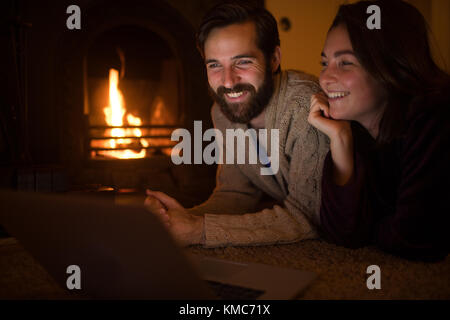 Coppia sorridente che usa il computer portatile nel soggiorno Foto Stock