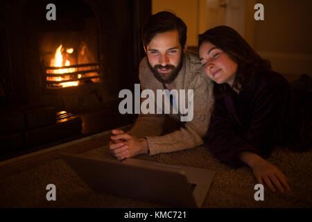 Coppia sorridente che usa il computer portatile nel soggiorno Foto Stock