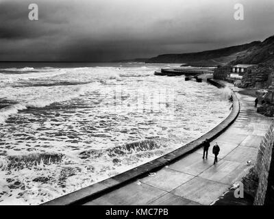 La gente a piedi dalla parete del mare in cattive condizioni atmosferiche in corrispondenza di alta marea in South Bay a Scarborough North Yorkshire, Inghilterra Foto Stock