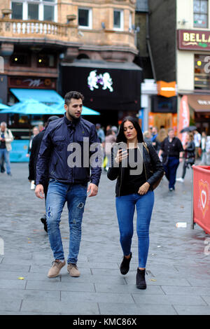 Dai capelli scuri giovane uomo caucasico e donna camminare insieme, Leicester Square, London, England, Regno Unito Foto Stock
