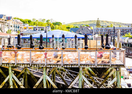 Bar Harbor, Stati Uniti d'America - 8 giugno 2017: ponte di legno dock, marina e il lungomare ristorante con persone mangiare seduti su sedie dalle tabelle nel centro di villaggio Foto Stock