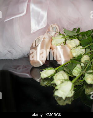 Satin scarpe da ballo, rosa tutu e rose fiori su fondo nero sfondo riflettente Foto Stock