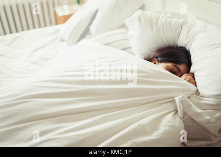 Stanco giovane donna che dorme nel letto Foto Stock