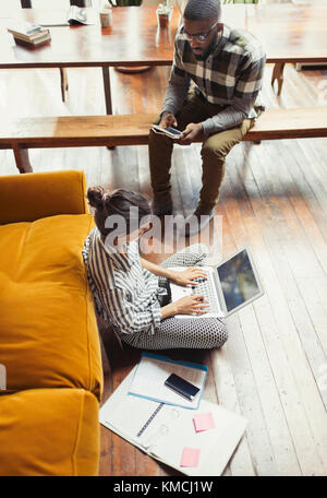 Freelance femminile che lavora su un computer portatile sul pavimento del soggiorno Foto Stock