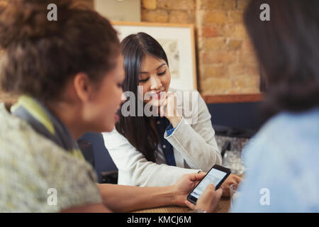 Giovani amici di sesso femminile che usano lo smartphone al bar Foto Stock
