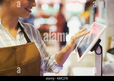 Cassa femminile che usa il registratore di cassa touch screen nel negozio di alimentari Foto Stock