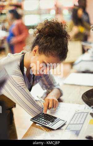 Cassiere femminile con calcolatrice in negozio Foto Stock